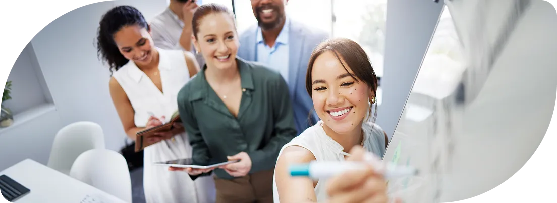 Equipe sorrindo em volta de um quadro branco, durante uma reunião de planejamento